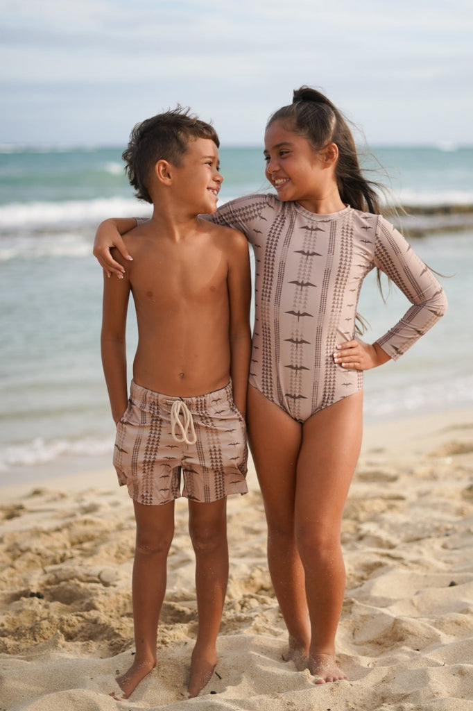 Two children standing on a beach with ocean in the background